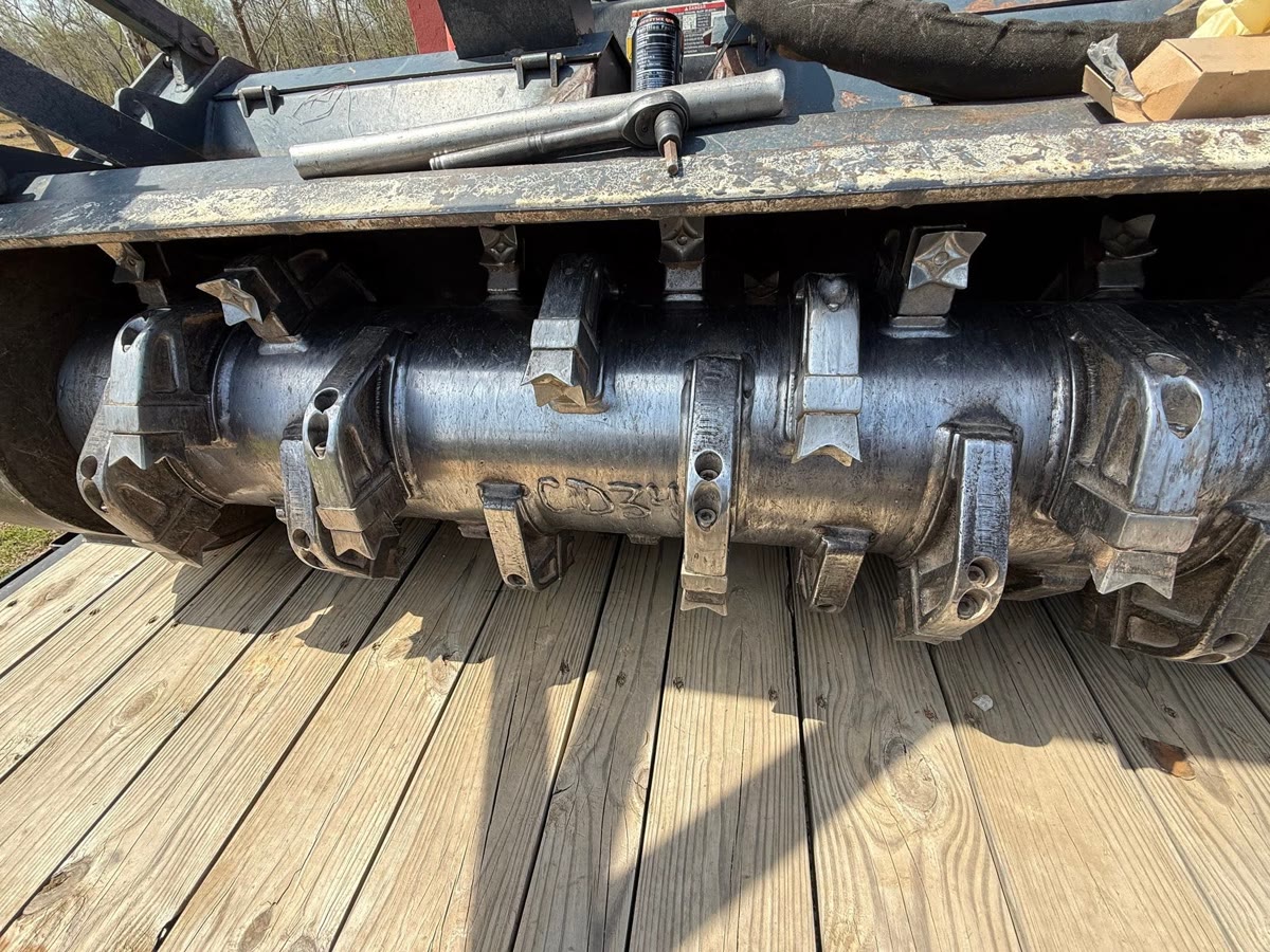 The mulcher head on a trailer deck, its rows of teeth in view.